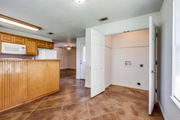 a view of a refrigerator in kitchen and an empty room