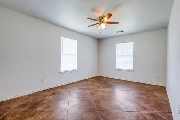an empty room with windows and fan