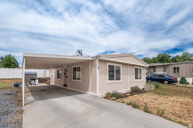 2600 North Hill Field Road, Unit 5 Layton, UT 84041 - Photo 2 of 33 Exterior featuring beige siding with white trim, a covered carport, a concrete driveway, and a white privacy fence