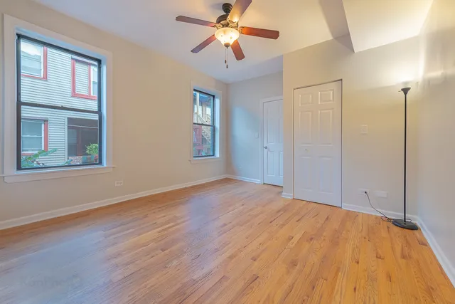 a view of empty room with wooden floor and fan