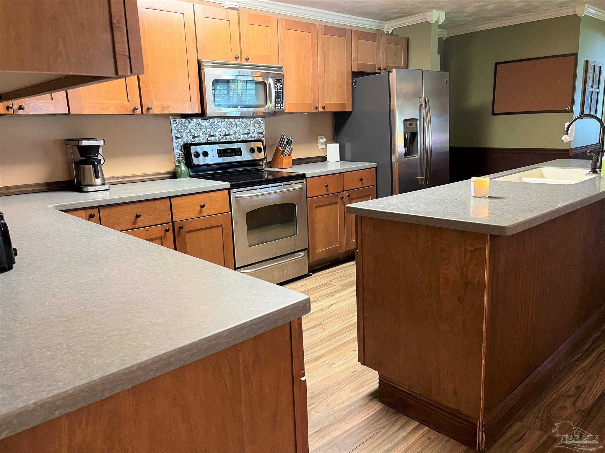 77 Hill Street Atmore, AL 36502 - Photo 11 of 30 a kitchen with stainless steel appliances a refrigerator a stove a sink and white cabinets