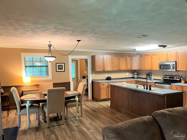a kitchen with stainless steel appliances granite countertop a table chairs sink and window