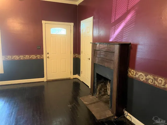 a view of an empty room with wooden floor and a fireplace