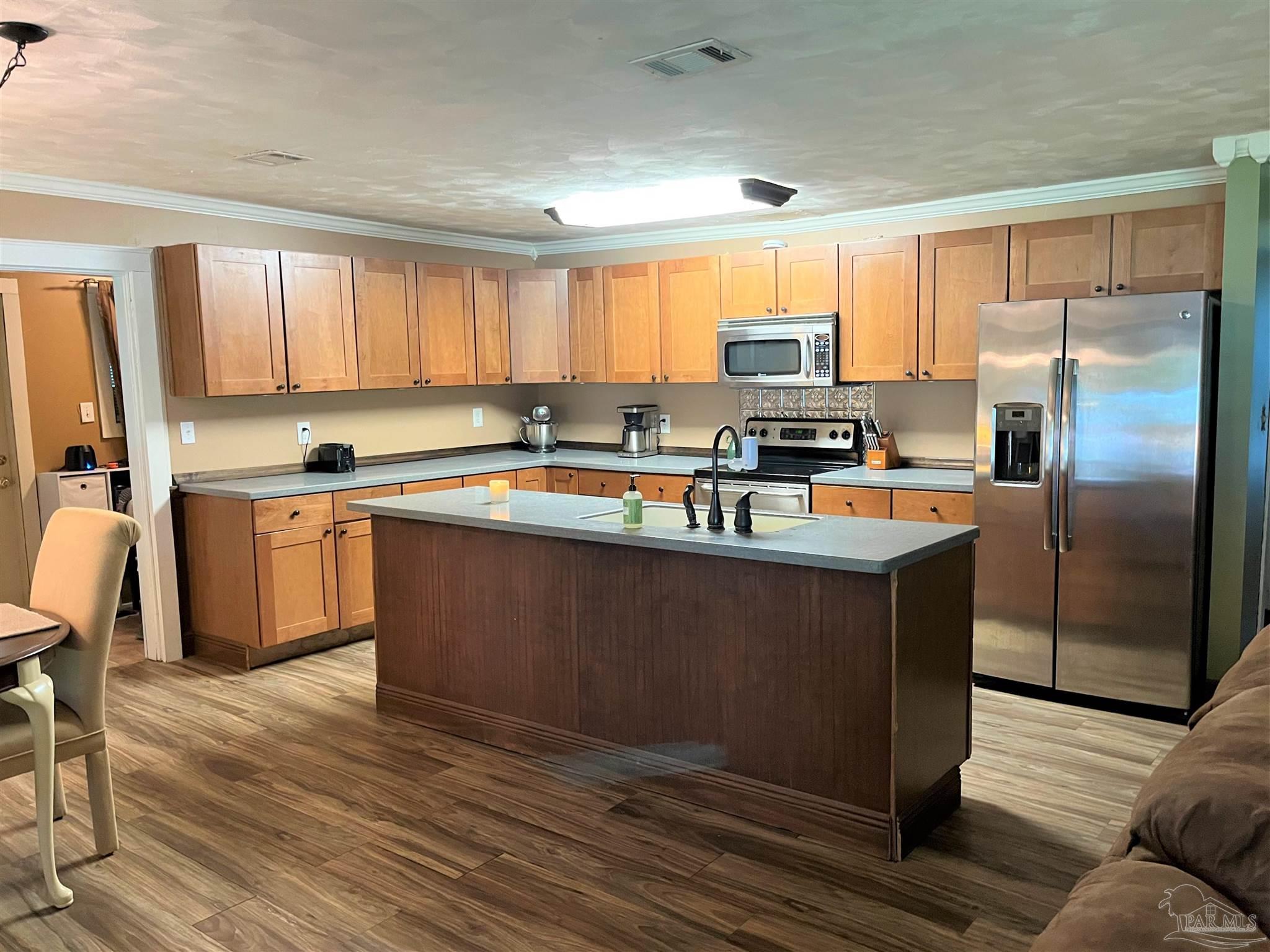 77 Hill Street Atmore, AL 36502 - Photo 9 of 30 a kitchen with stainless steel appliances granite countertop a refrigerator a sink dishwasher a stove with wooden cabinets and wooden floor