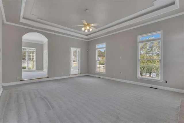 an empty room with a chandelier fan and windows