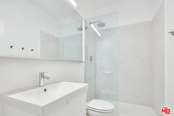 a bathroom with a sink a toilet and shower