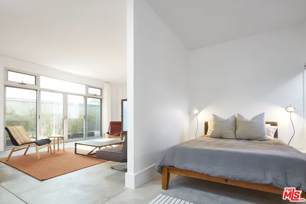 a bedroom with a bed and large windows