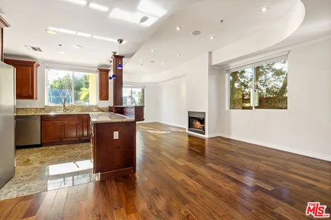 a view of kitchen with stainless steel appliances granite countertop a stove a sink a refrigerator and wooden floor