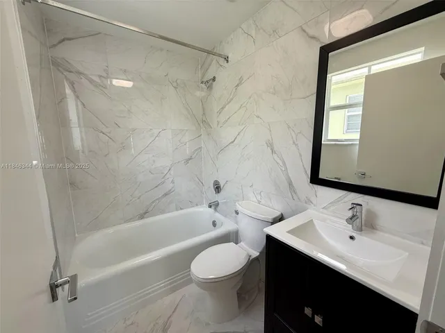 a bathroom with a bathtub shower sink vanity mirror and toilet