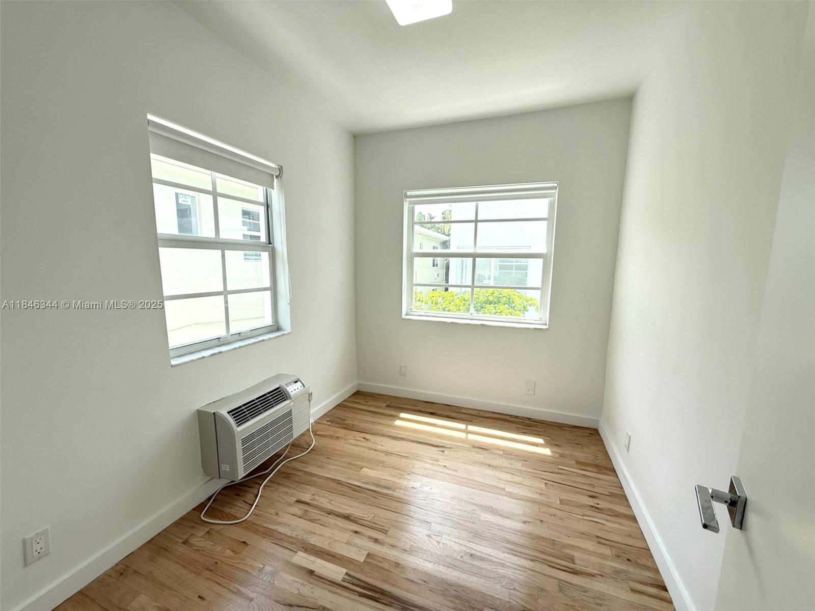 1552 Euclid Avenue, Unit 3 Miami Beach, FL 33139 - Photo 7 of 13 an empty room with wooden floor and windows