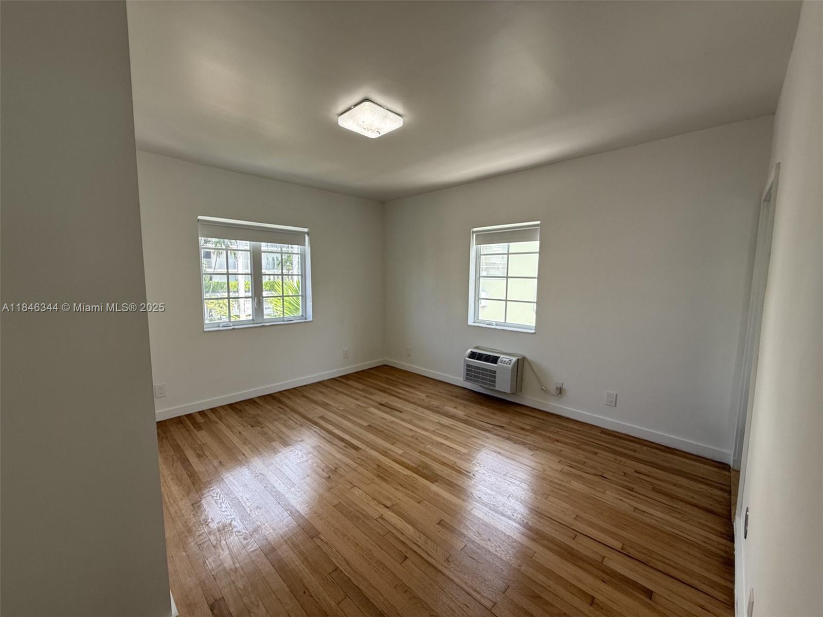 1552 Euclid Avenue, Unit 3 Miami Beach, FL 33139 - Photo 9 of 13 an empty room with wooden floor and windows