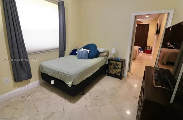 a living room with a bed furniture and a flat tv screen on a dresser