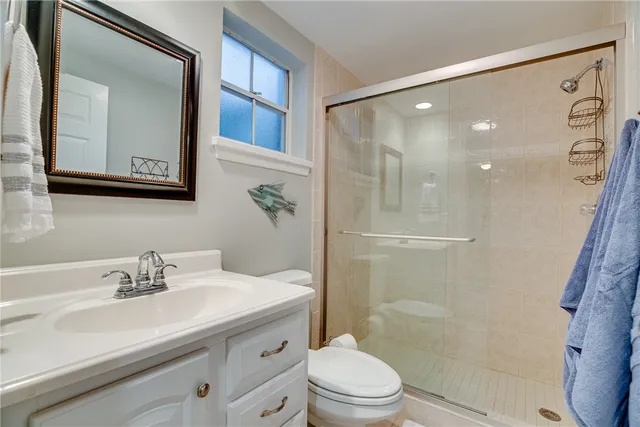 a bathroom with a sink a toilet a mirror and shower