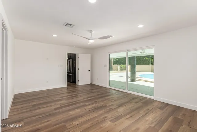 an empty room with wooden floor and windows