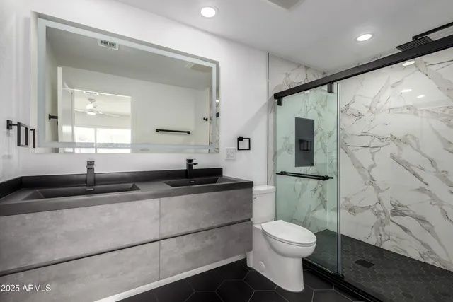 a bathroom with a granite countertop sink toilet a mirror and shower