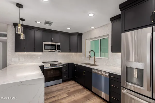 a kitchen with stainless steel appliances granite countertop a sink a stove and a refrigerator