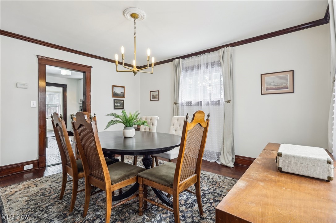 17901 Windward Road Cleveland, OH 44119 - Photo 7 of 33 Dining area with a notable chandelier, dark wood-type flooring, and ornamental molding