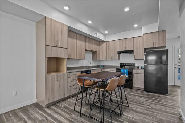 a kitchen with stainless steel appliances a refrigerator a stove a sink and white cabinets with wooden floor