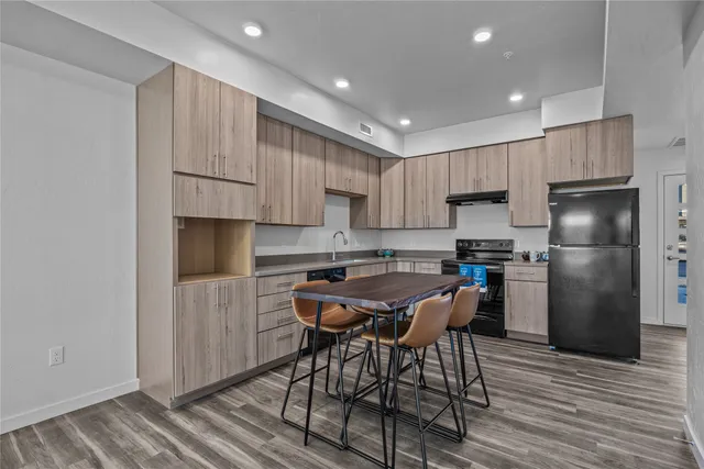 a kitchen with stainless steel appliances a refrigerator a stove a sink and white cabinets with wooden floor