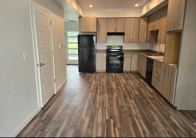 a kitchen with a refrigerator a stove top oven and wooden floor