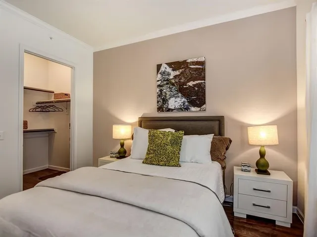 a bedroom with a bed and a lamp on dresser