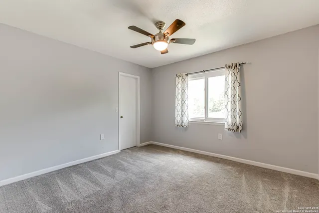 an empty room with ceiling fan and windows