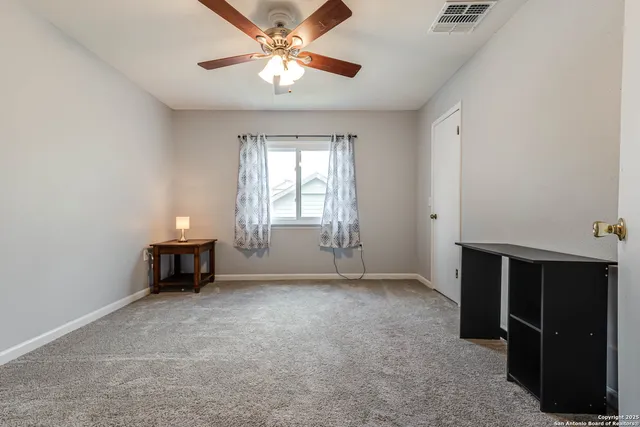 an empty room with windows and a ceiling fan