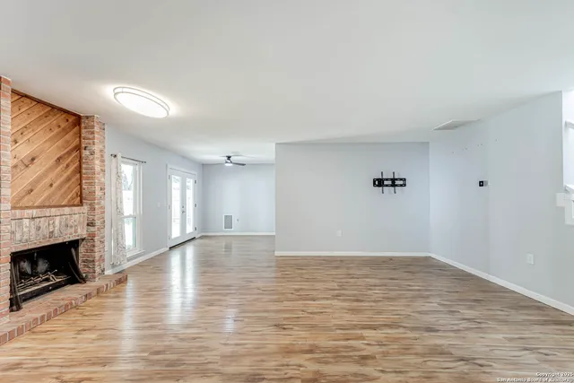 a view of empty room with wooden floor and fireplace