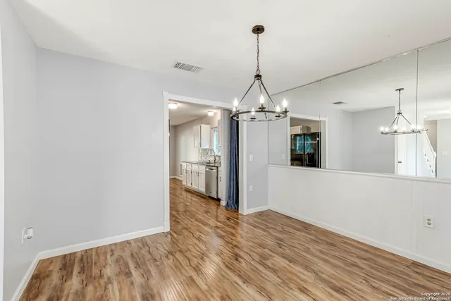 a view of a big room with wooden floor staircase and a chandelier