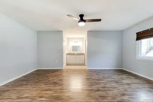 a view of empty room with wooden floor and fan