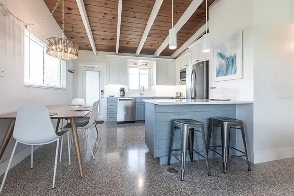 a kitchen with kitchen island a dining table chairs sink and wooden floor