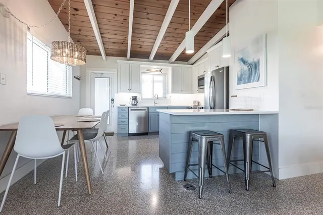 a kitchen with kitchen island a dining table chairs sink and wooden floor