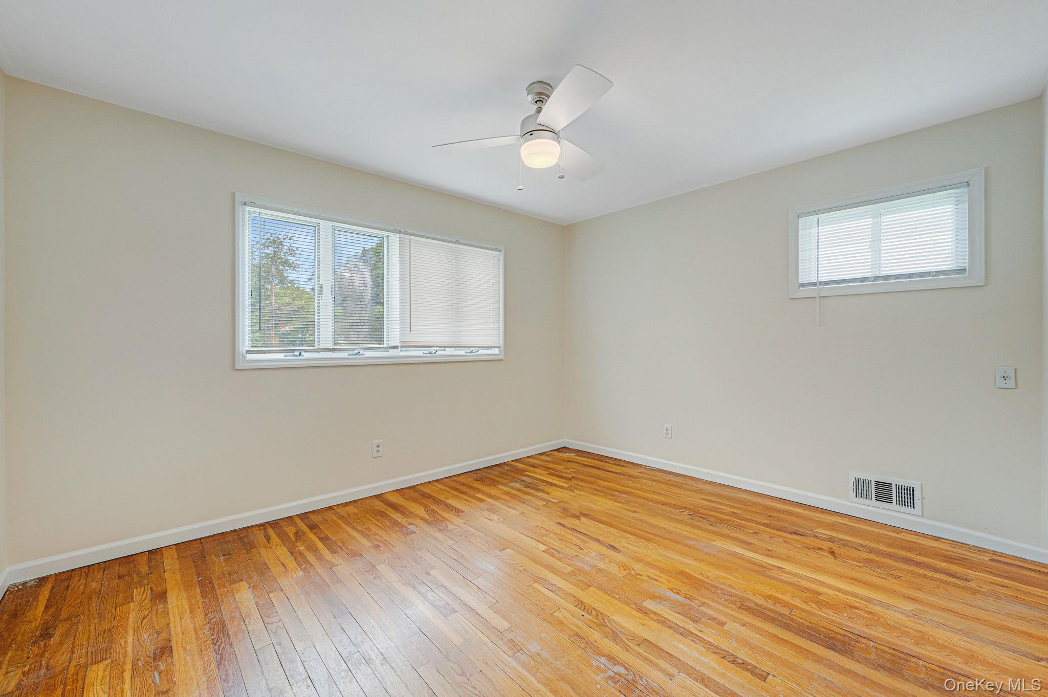 10 Laurie Road Brentwood, NY 11717 - Photo 13 of 29 Empty room with healthy amount of natural light, light wood finished floors, and a ceiling fan