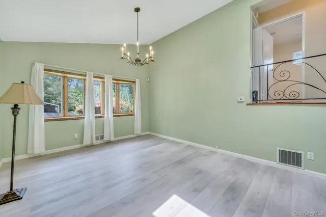 a view of an empty room with window and wooden floor