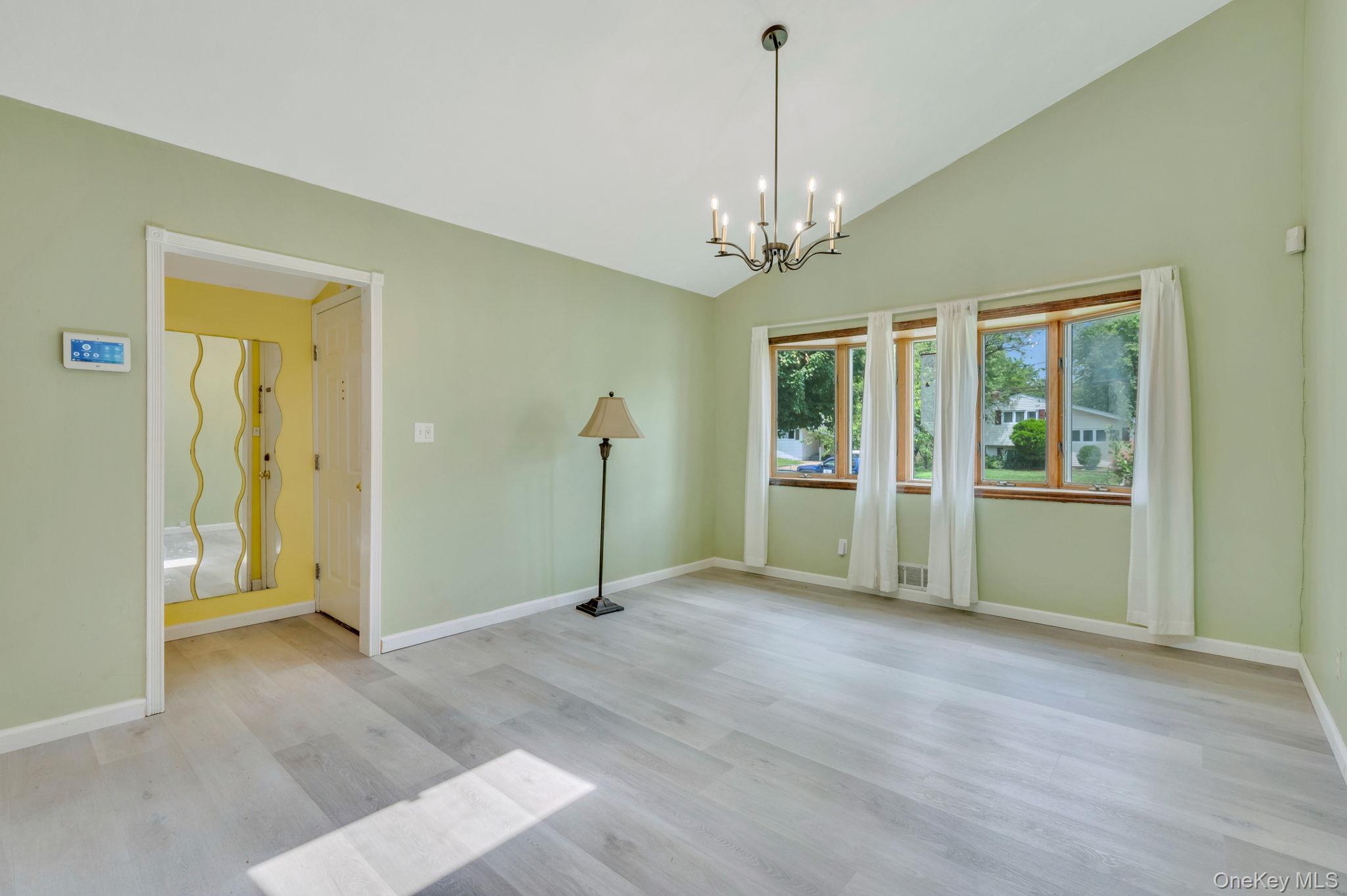 10 Laurie Road Brentwood, NY 11717 - Photo 4 of 29 Unfurnished room with a chandelier, wood finished floors, and high vaulted ceiling