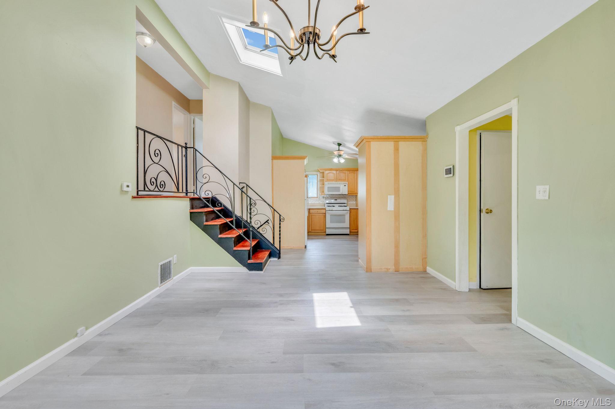10 Laurie Road Brentwood, NY 11717 - Photo 5 of 29 Entrance foyer featuring lofted ceiling, a chandelier, stairway, and light wood-style floors
