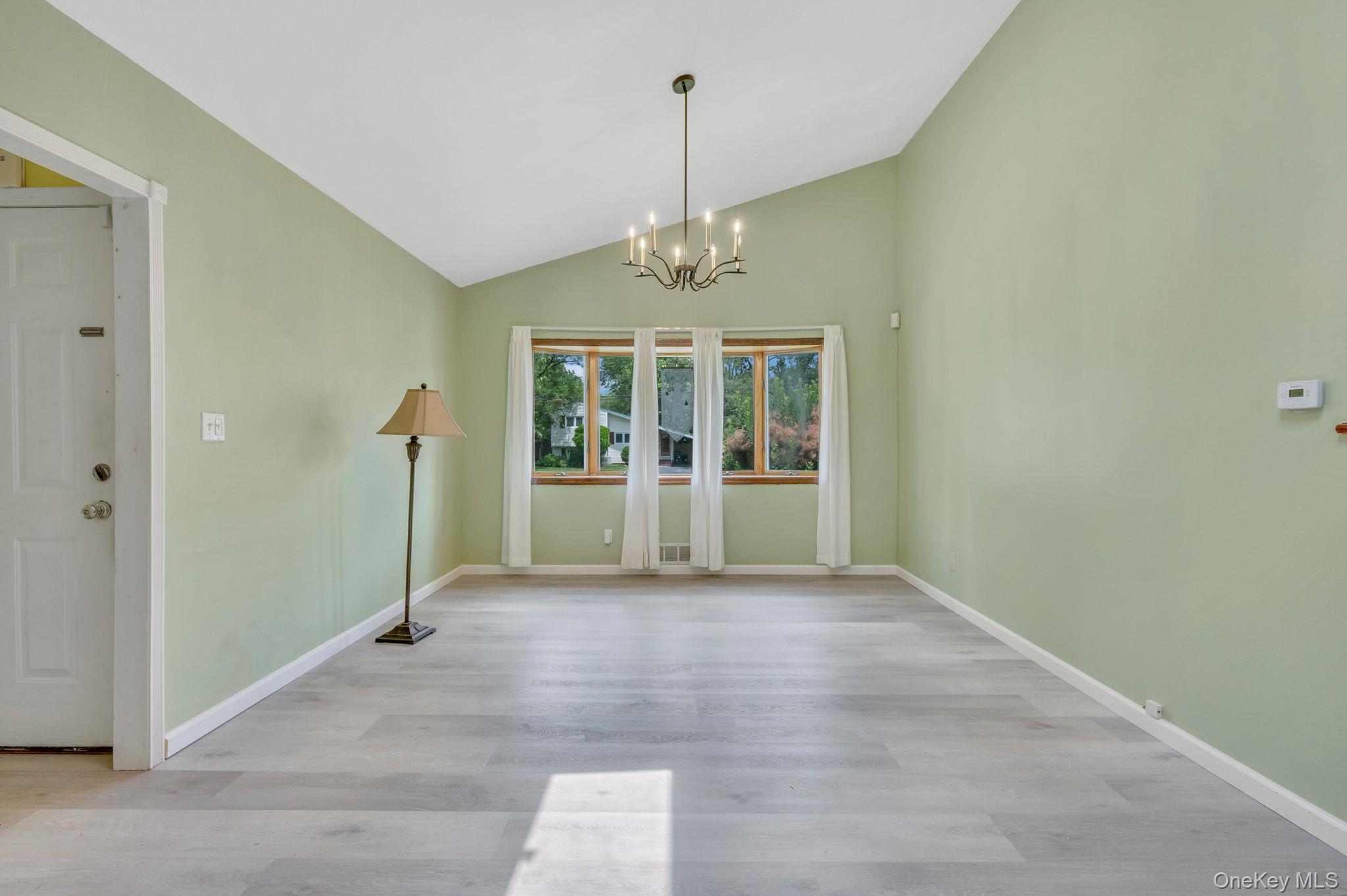 10 Laurie Road Brentwood, NY 11717 - Photo 6 of 29 Unfurnished dining area with a chandelier, light wood-style floors, and high vaulted ceiling