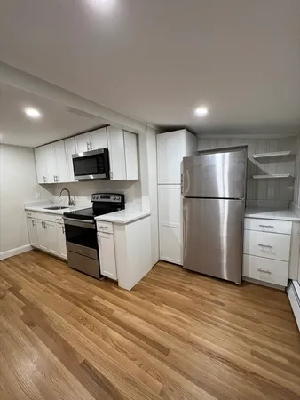 a kitchen with a refrigerator cabinets and wooden floor