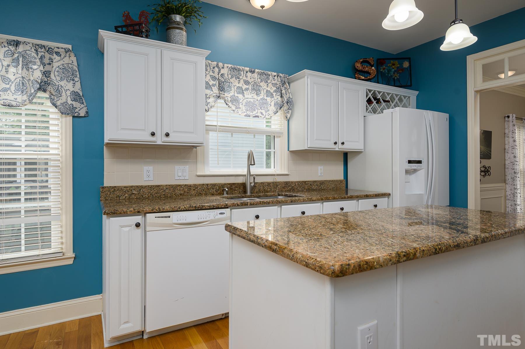 701 Modena Drive Cary, NC 27513 - Photo 12 of 39 a kitchen with granite countertop a sink a stove and a wooden cabinets