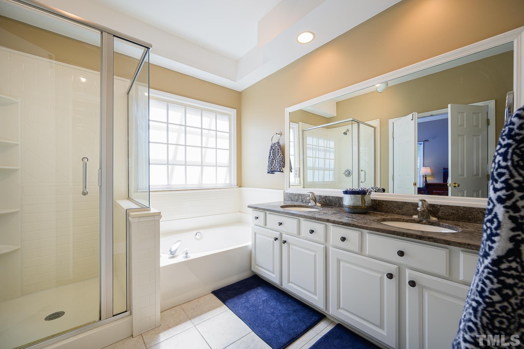 701 Modena Drive Cary, NC 27513 - Photo 23 of 39 a spacious bathroom with a granite countertop sink mirror and a bathtub