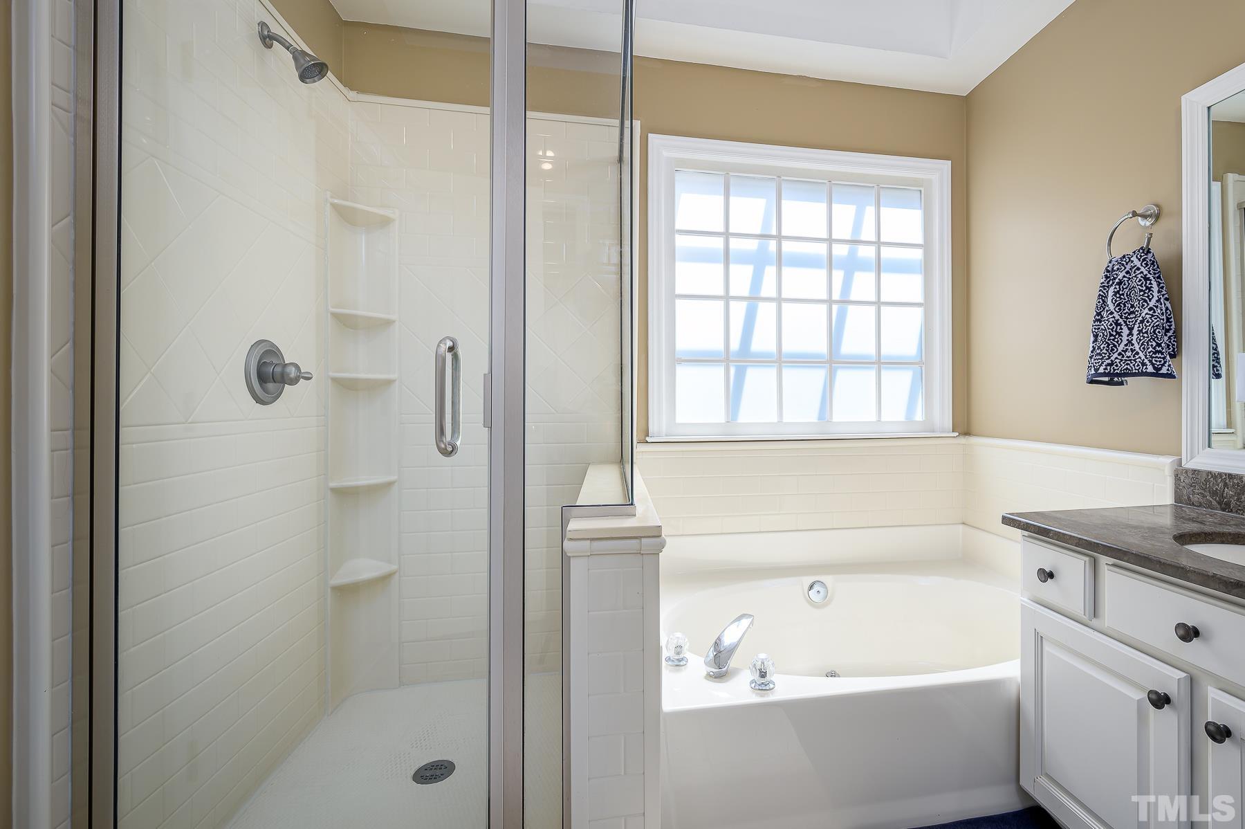 701 Modena Drive Cary, NC 27513 - Photo 24 of 39 a bathroom with a bathtub a shower a sink and a window