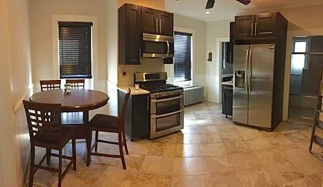 a kitchen with granite countertop a table chairs stove and refrigerator