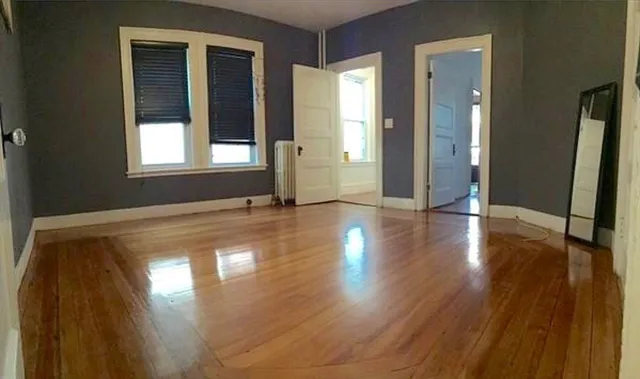 a view of empty room with window and wooden floor