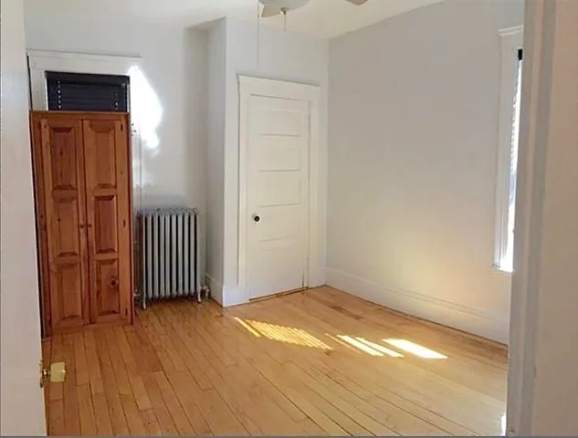 an empty room with wooden floor door and windows