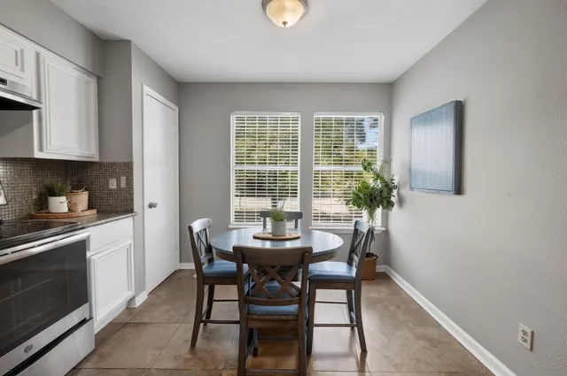 a view of backyard of a house with table and chairs potted plants and large tree