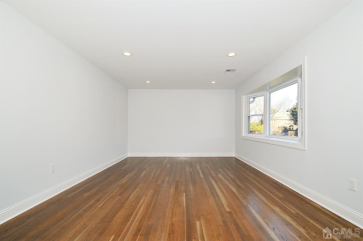 24 Prescott Street Edison, NJ 08817 - Photo 3 of 27 an empty room with wooden floor and windows