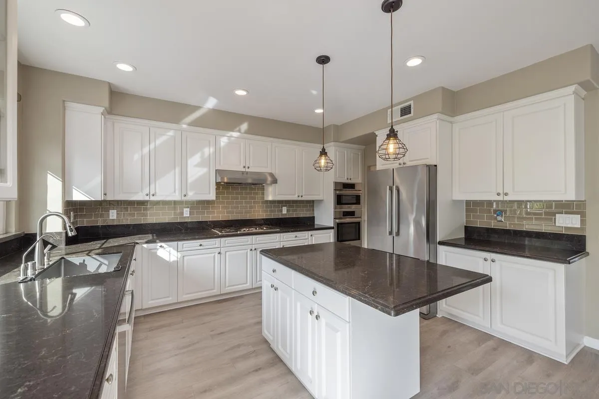 6013 Oakgate Row La Jolla, CA 92037 - Photo 20 of 50 a kitchen with stainless steel appliances granite countertop a sink stove and refrigerator