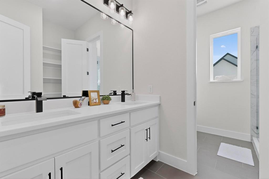 4961 County Road 1098 Celeste, TX 75423 - Photo 25 of 40 Full bath with double vanity, dark tile patterned flooring, and a marble finish shower
