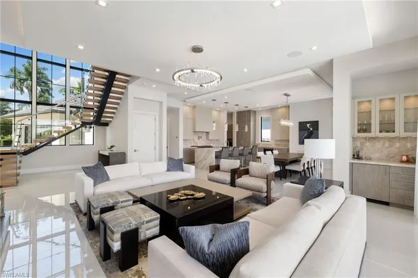a living room with furniture kitchen view and large windows