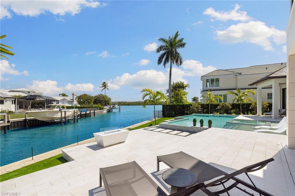 2345 Tarpon Road Naples, FL 34102 - Photo 18 of 43 a view of a patio with table and chairs floor to ceiling window and palm tree